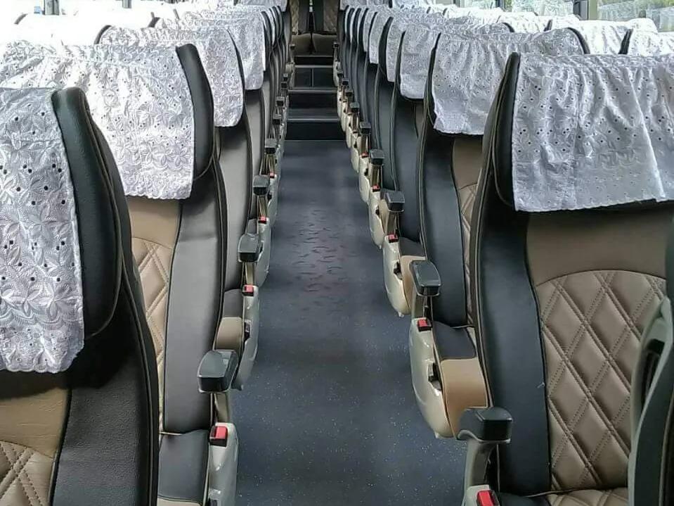 Looking down the aisle of a Skylight Buslines coach between rows of reclining seats