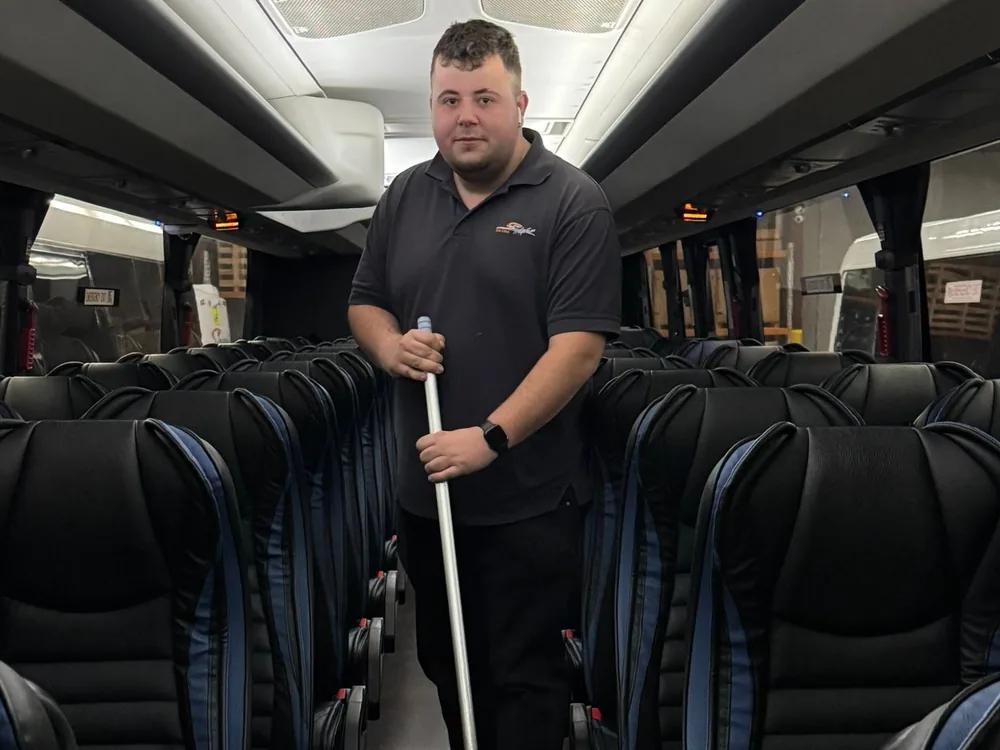 A Skylight Buslines team member cleaning the aisle of a coach between trips